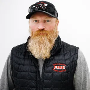 A man with a long red beard and sunglasses on top of his head with a baseball cap