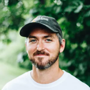 A man with a baseball cap grins