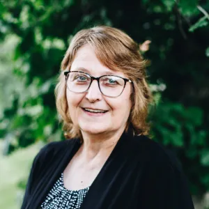 A woman with glasses smiles