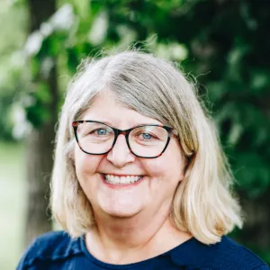 A woman with glasses smiles