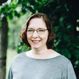 A woman with glasses smiles