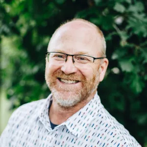 A man with glasses and a beard smiles