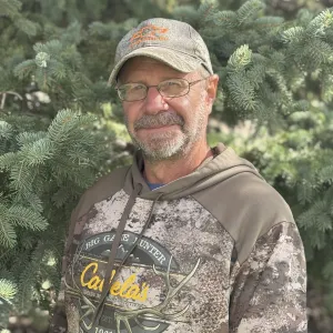 A man in a ballcap and glasses grinning