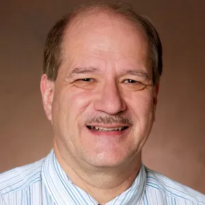 Gregory Oswald smiling confidently at the camera