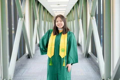 Nguyen smiling in commencement gown