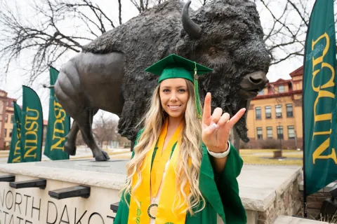 A student poses by the Bison statue