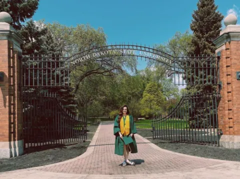 A student stands near the font gate of NDSU