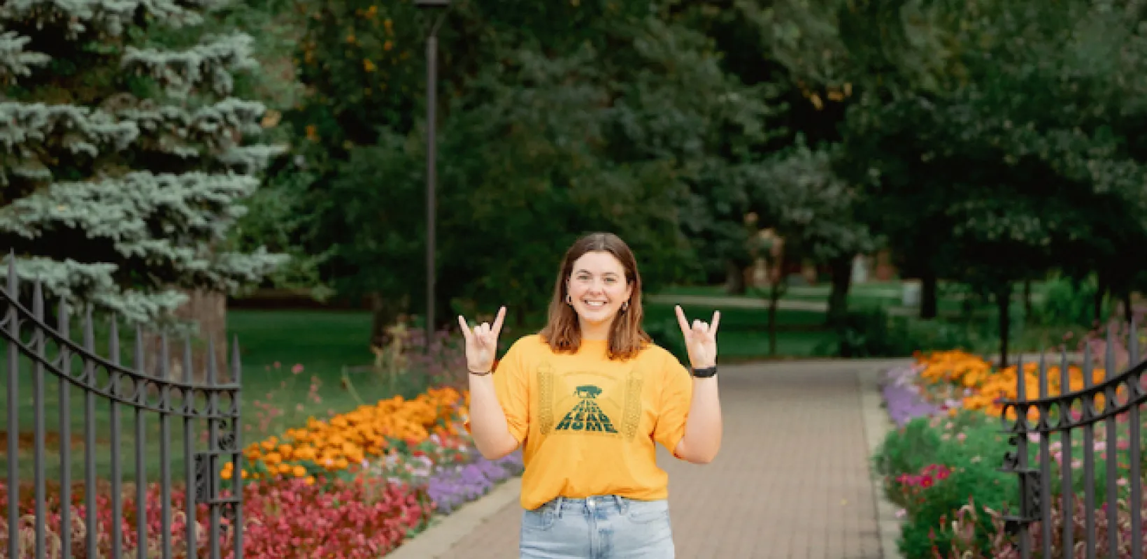 student Kaylee Weigel in front of the NDSU gates
