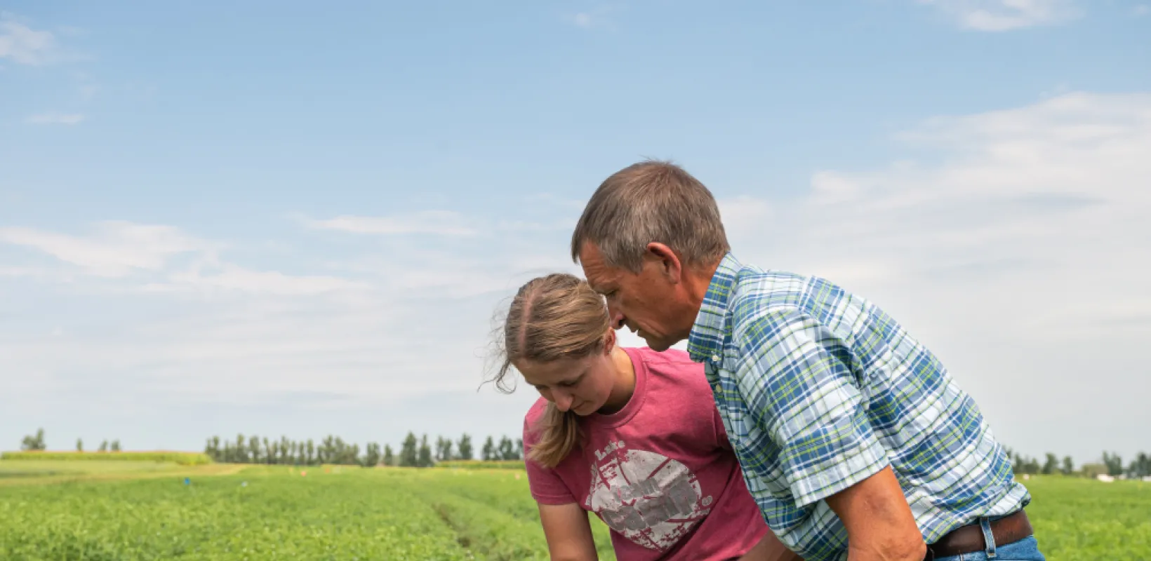 student working with a professor in a field