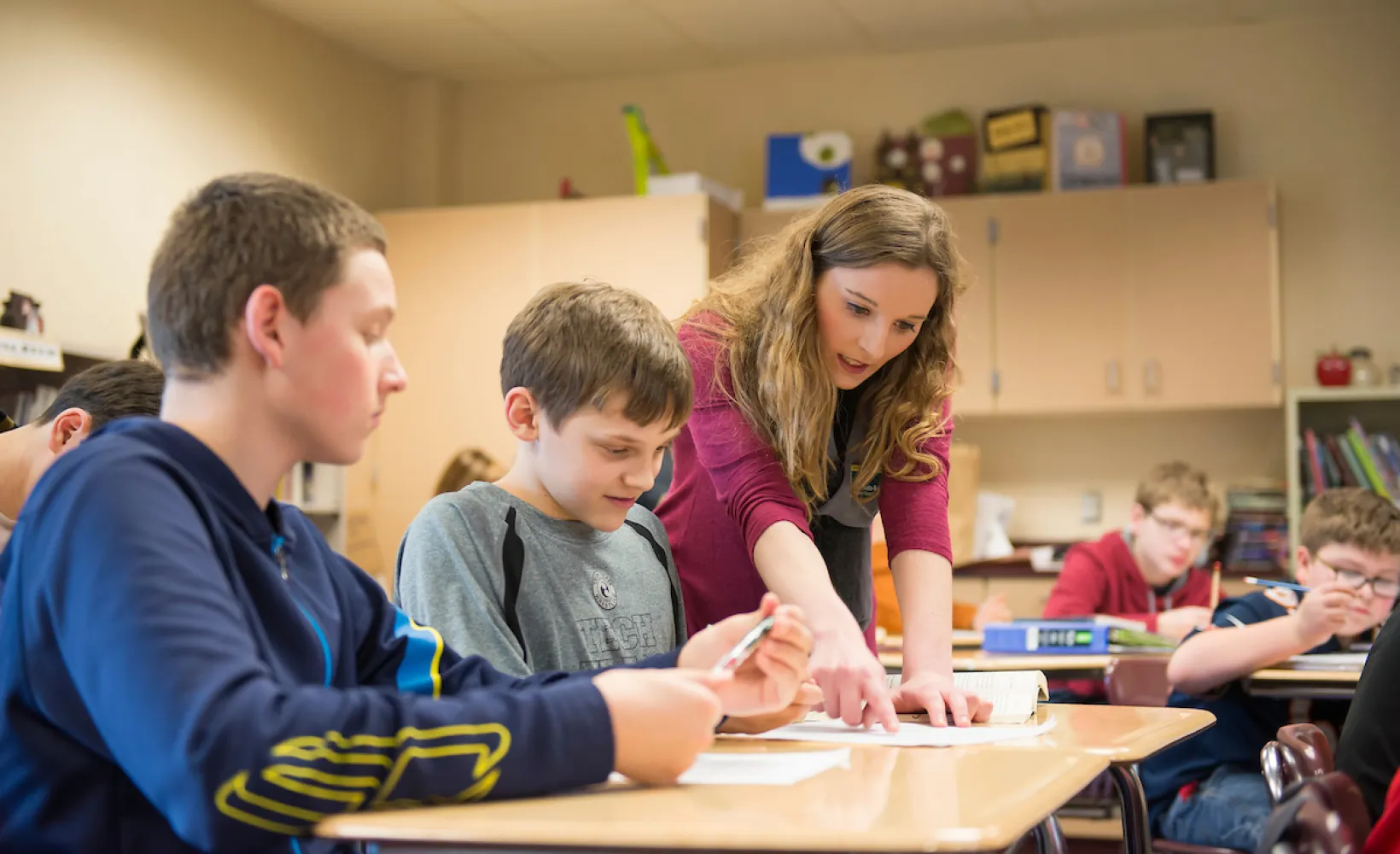 Education student helping young students in the classroom as part of student teaching
