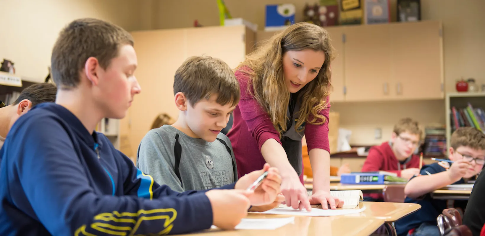 teacher helping students with a project in class