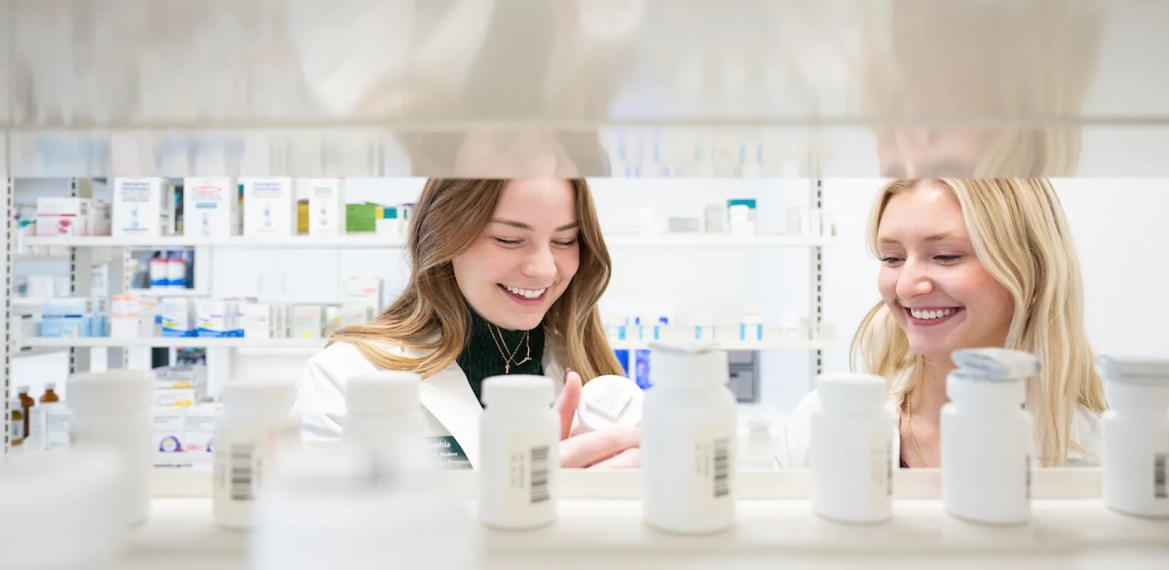 Two pharmacists looking at medications on a shelf in a pharacy