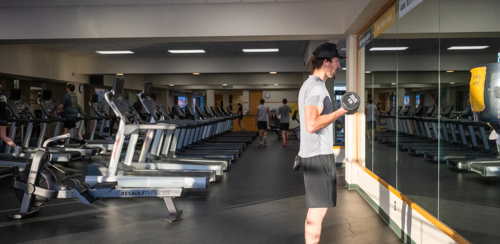 Student lifting weights in the Wellness Center by treadmills