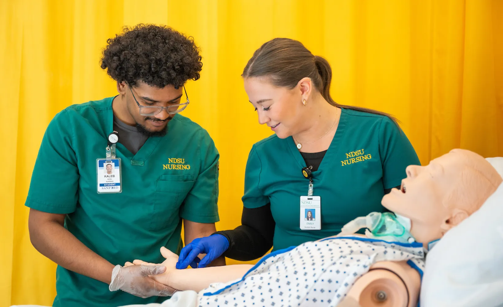 nursing students practicing patient care using a mannequin