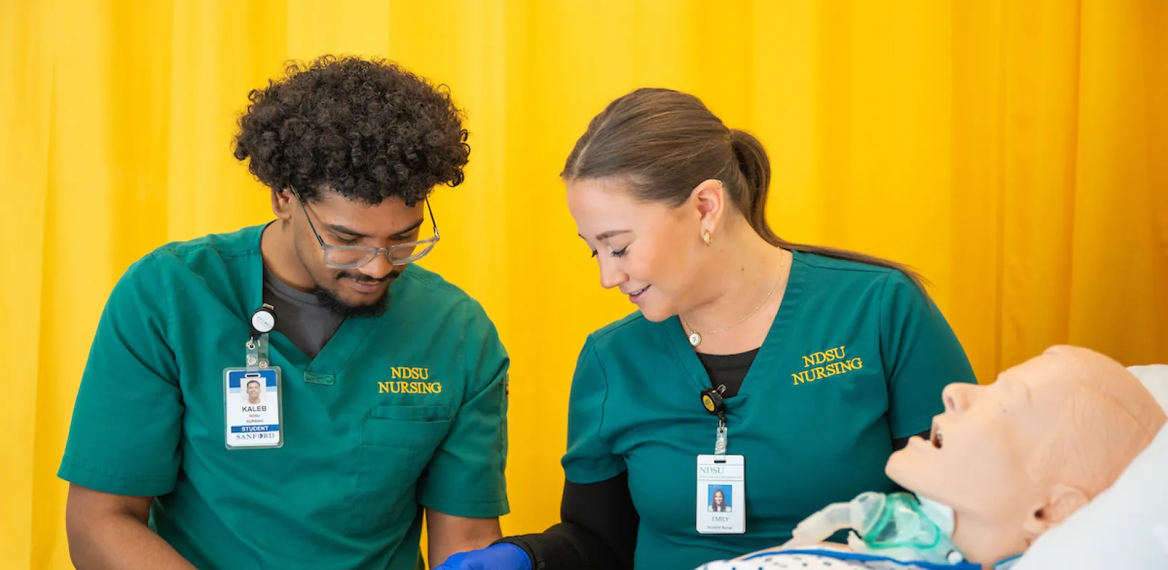 nursing students practicing a procedure on a training manikin