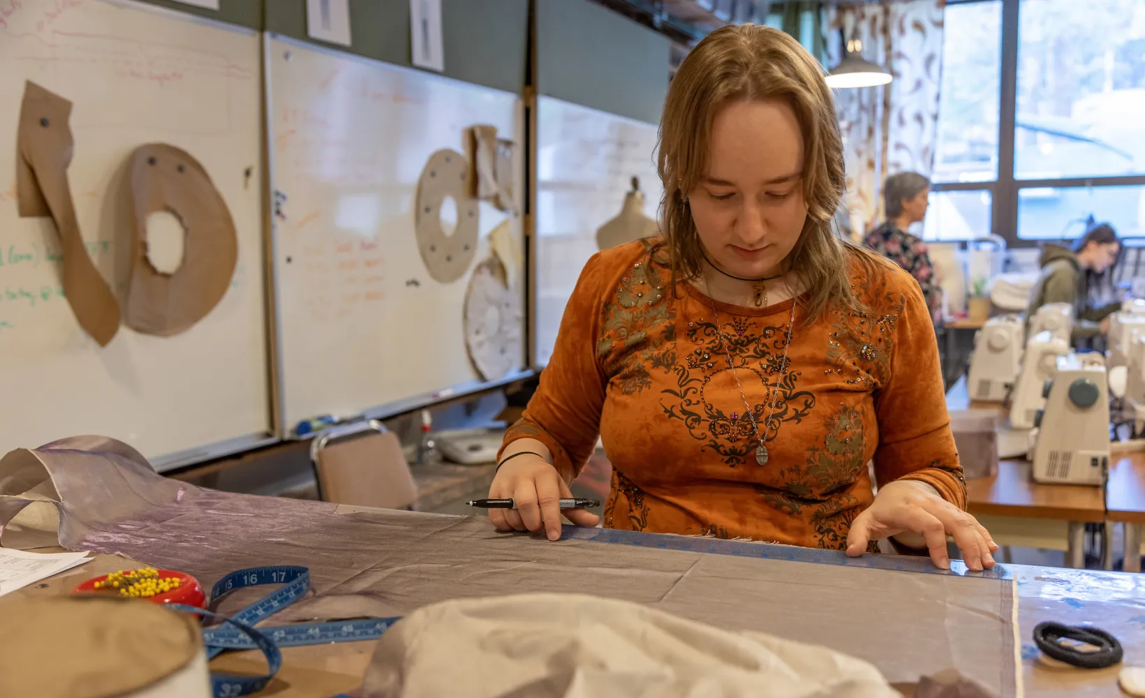student marking and cutting fabric for theatre costume