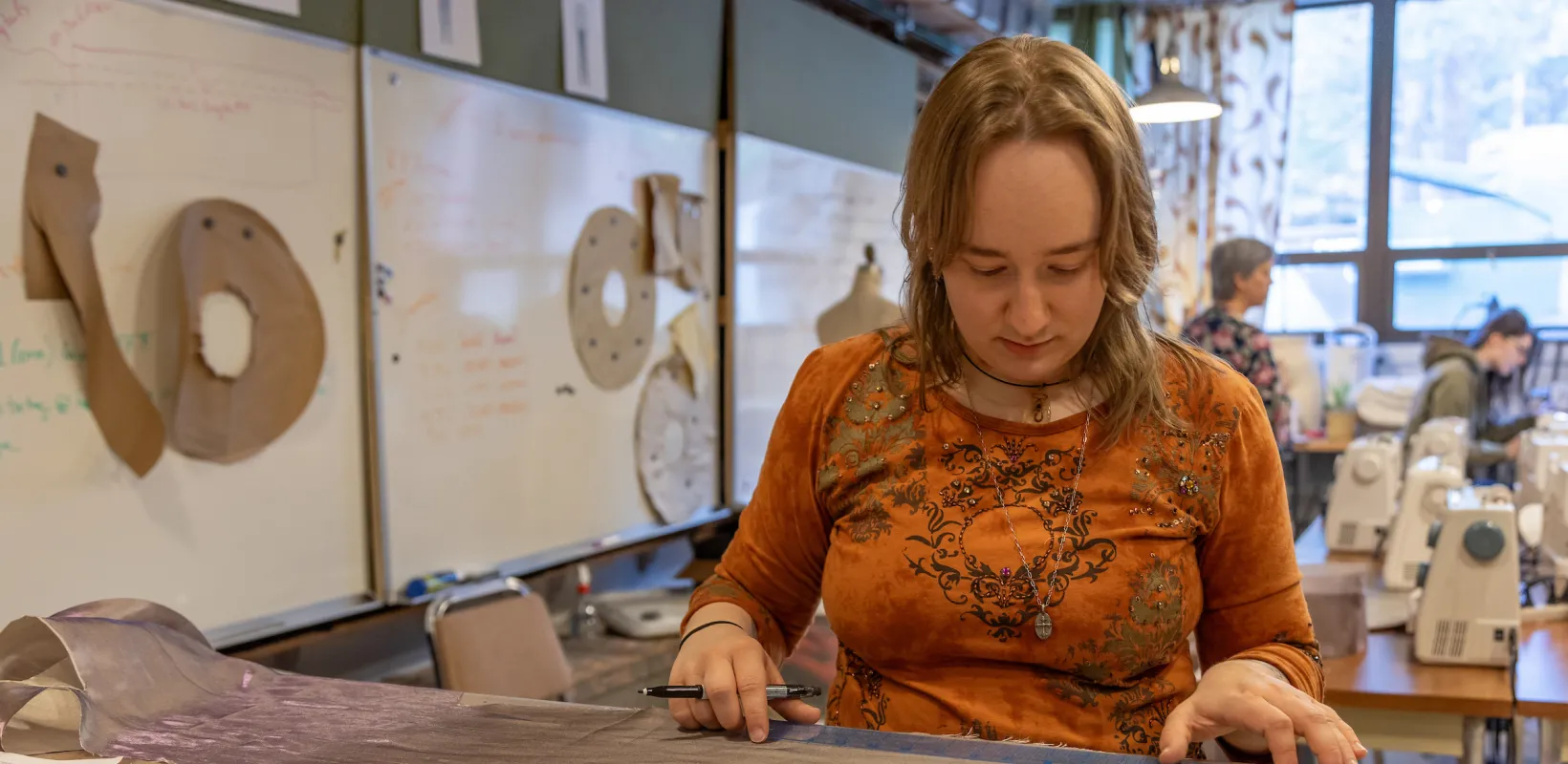 student marking and cutting fabric for theatre costume