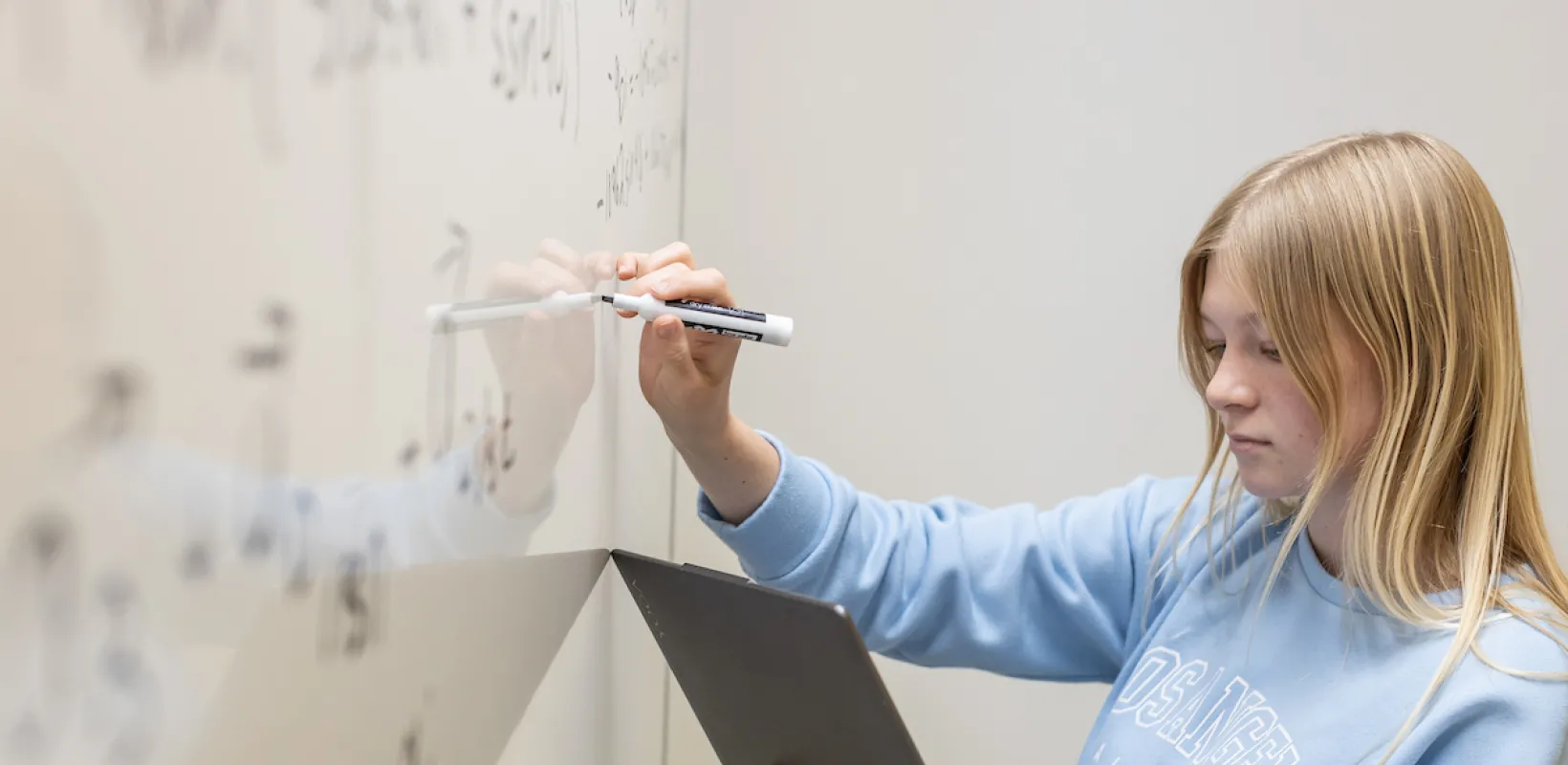 student working on a math equation on a whiteboard