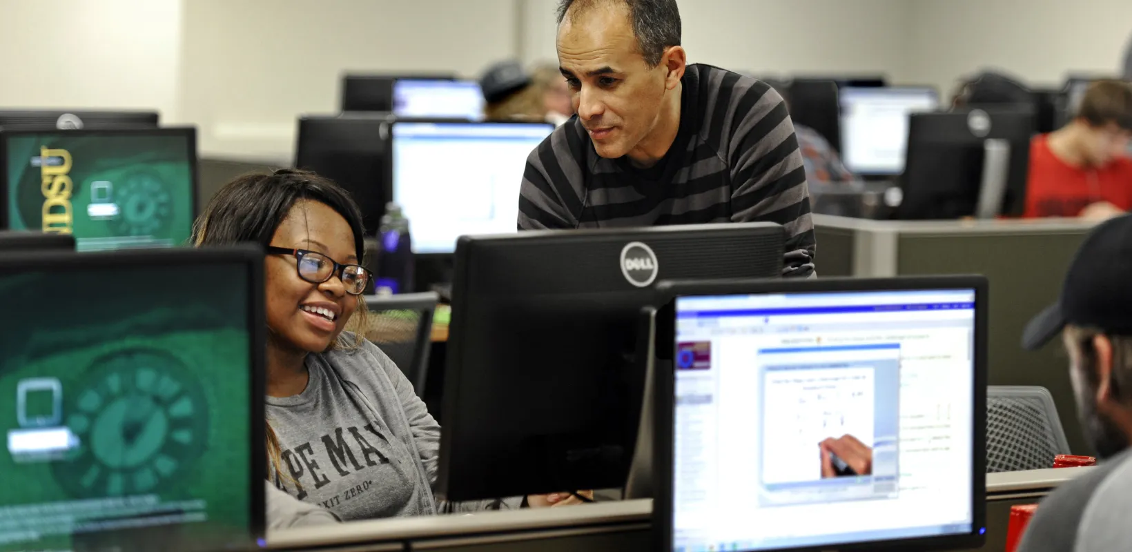 Instructor helping a student at her computer in a computer lab.
