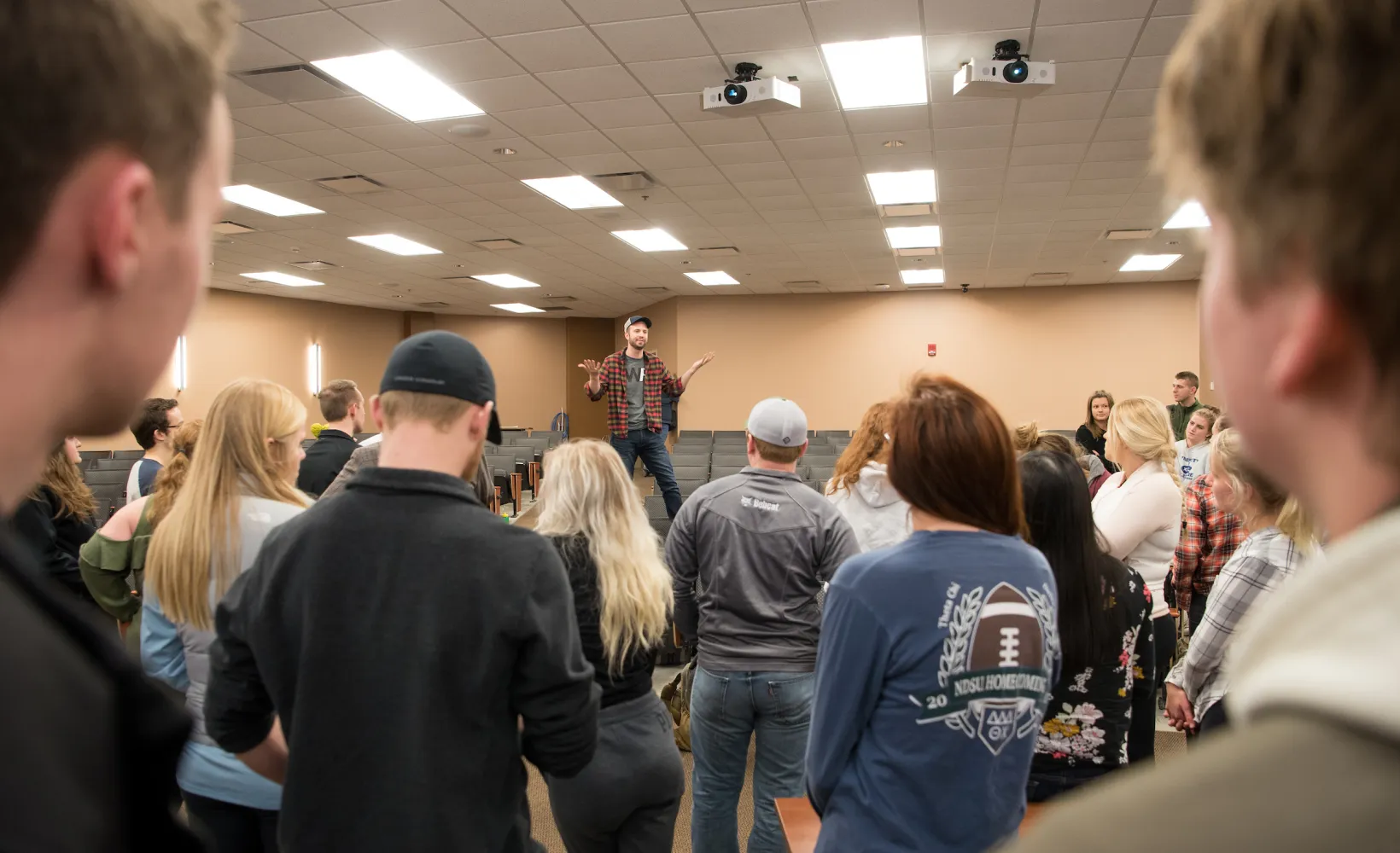 man speaking to a large group of people in a classroom