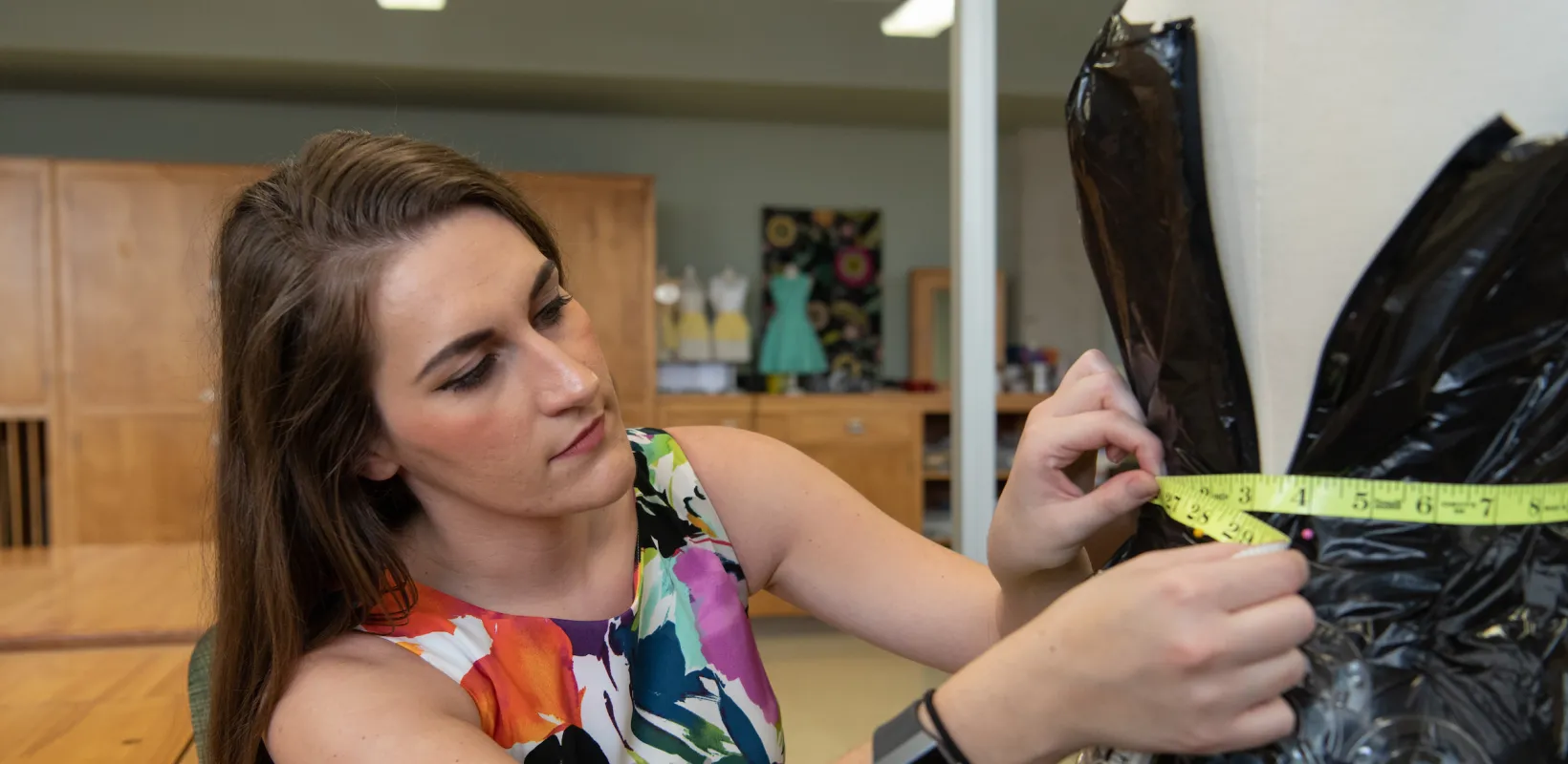 student measuring an apparel project on a dress form