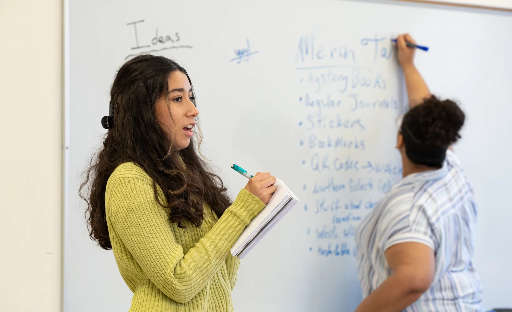 students giving a presentation and writing on a white board during a creative writing class