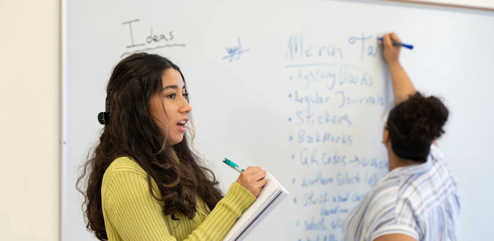 students discussing a topic in class and on a whiteboard