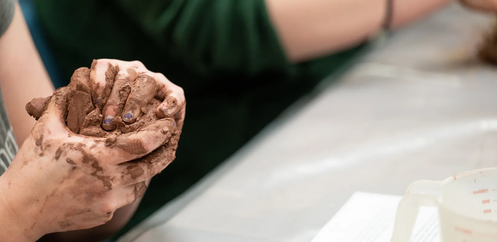 student working with wet clay in an archeology class