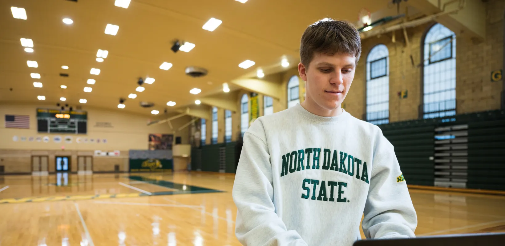 student working on a laptop in a sports arena