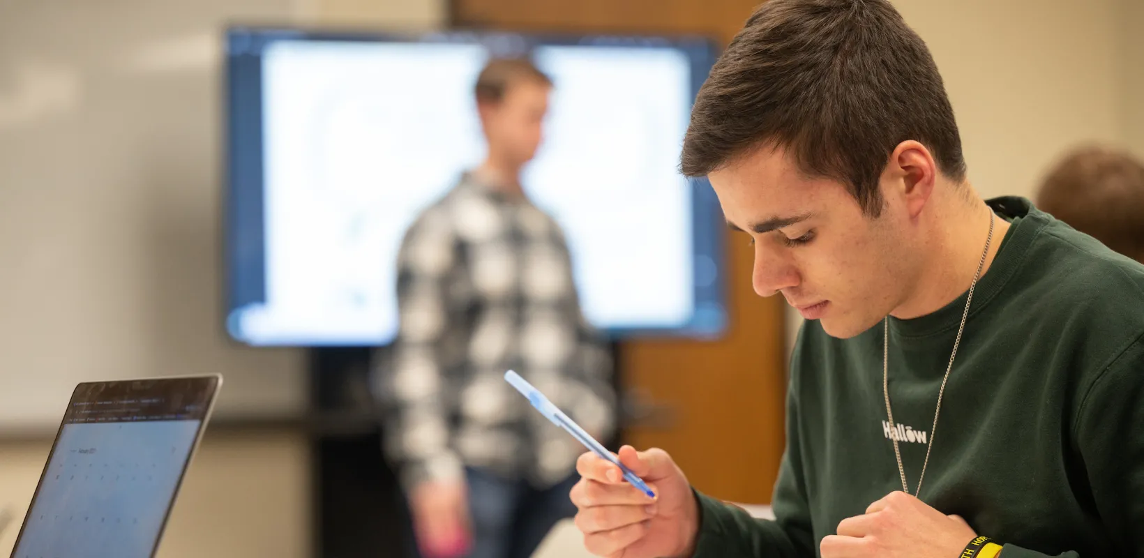 student writing on paper in class