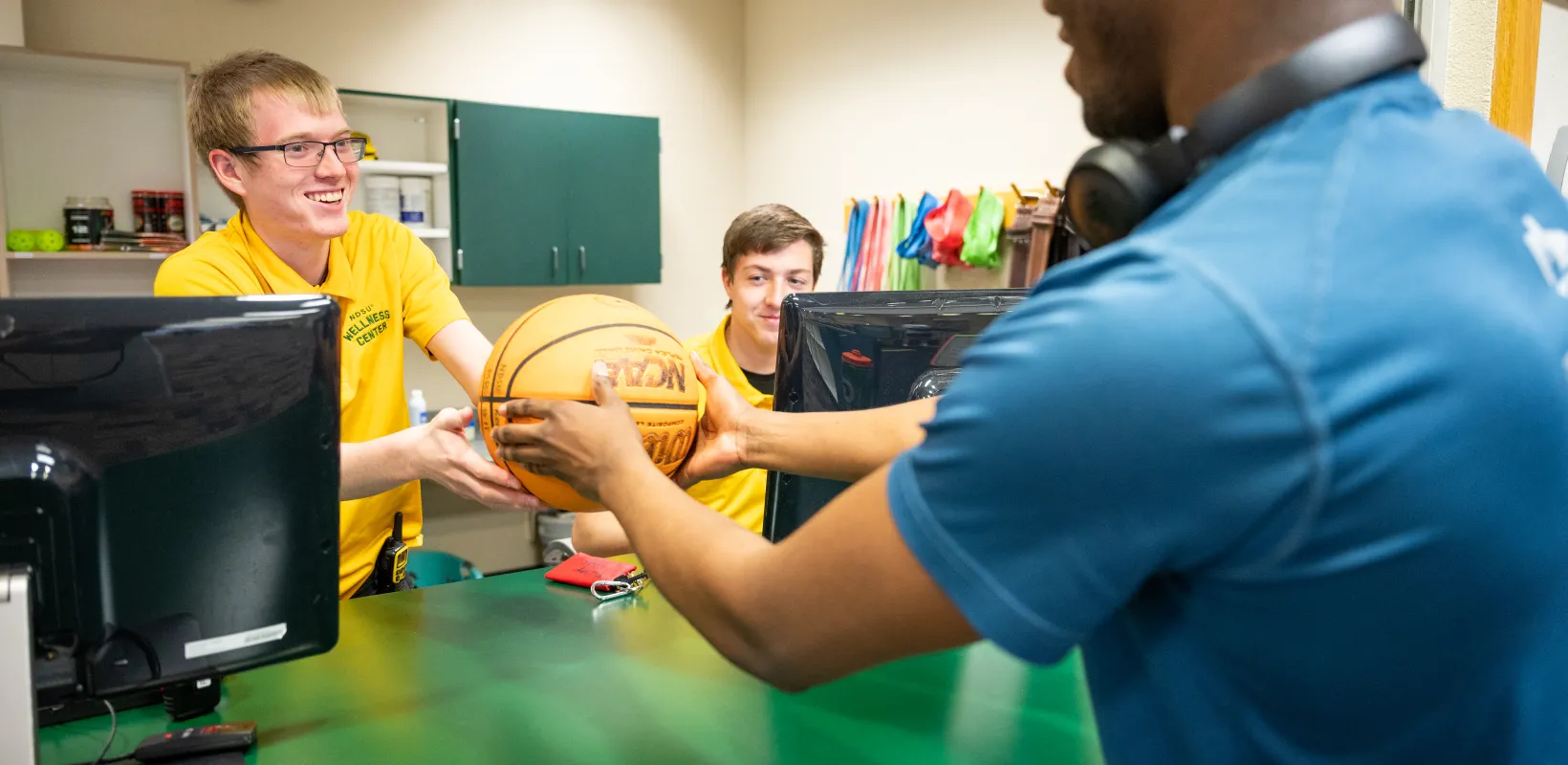 Student worker handing basketball to Wellness Center member