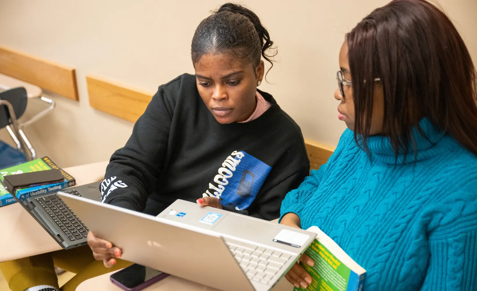 Graduate English students working together on a laptop during class