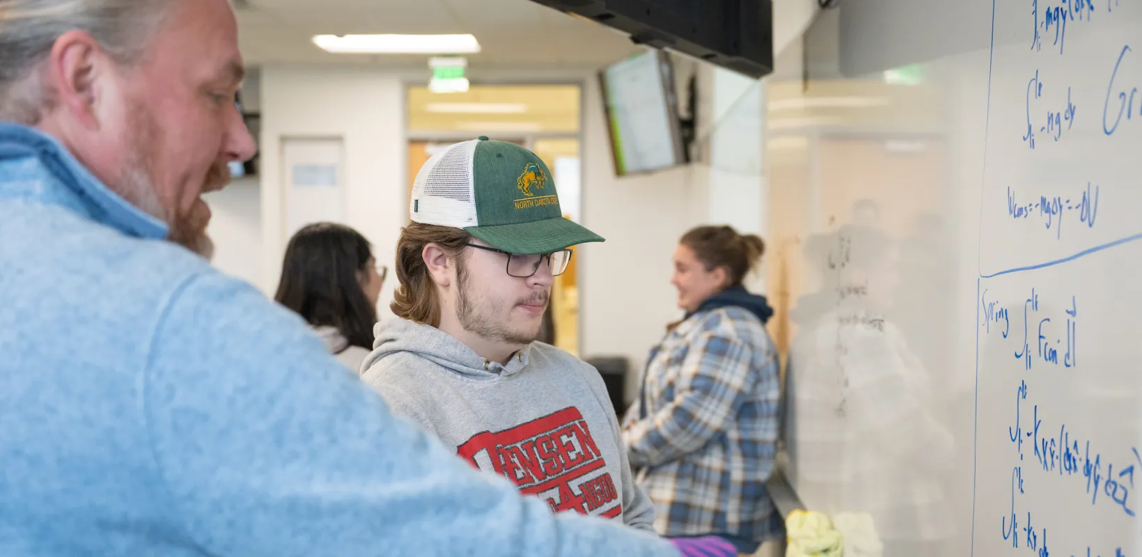 professor working with a student at a whiteboard