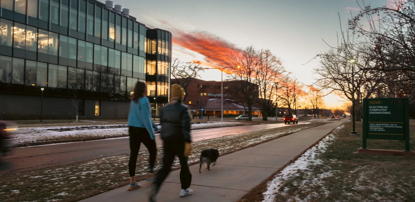 two students walking a dog on winter day