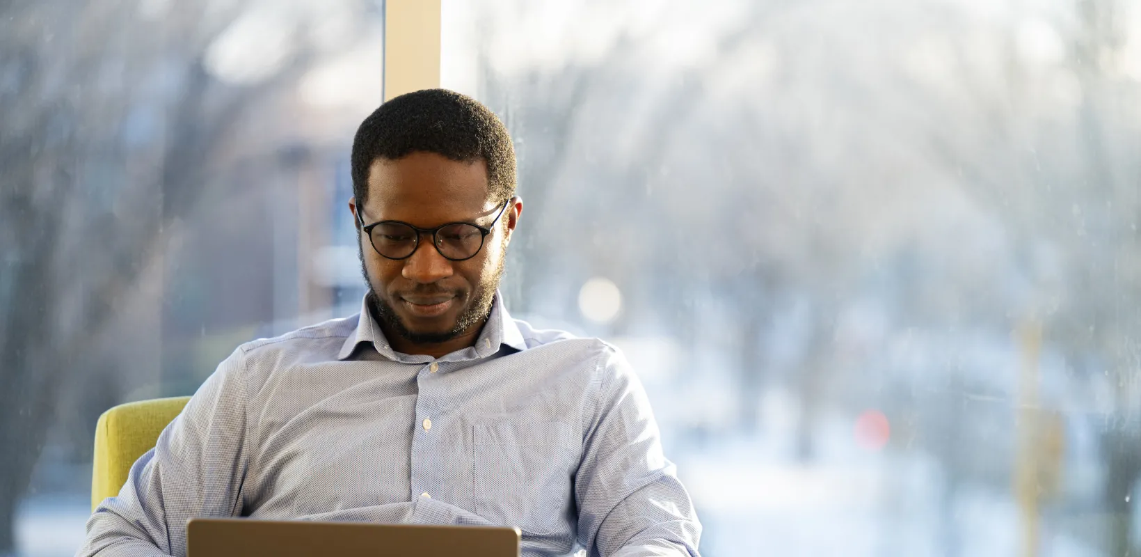 student working on a laptop in front of a window