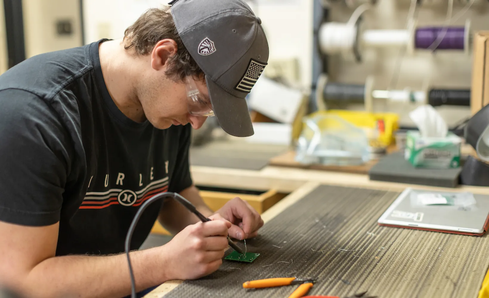 student working on a circuit board with a soldering iron