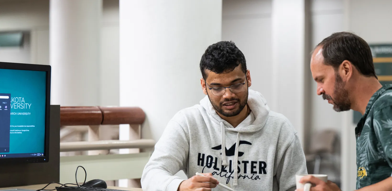 student working with a professor reviewing a project on a tablet