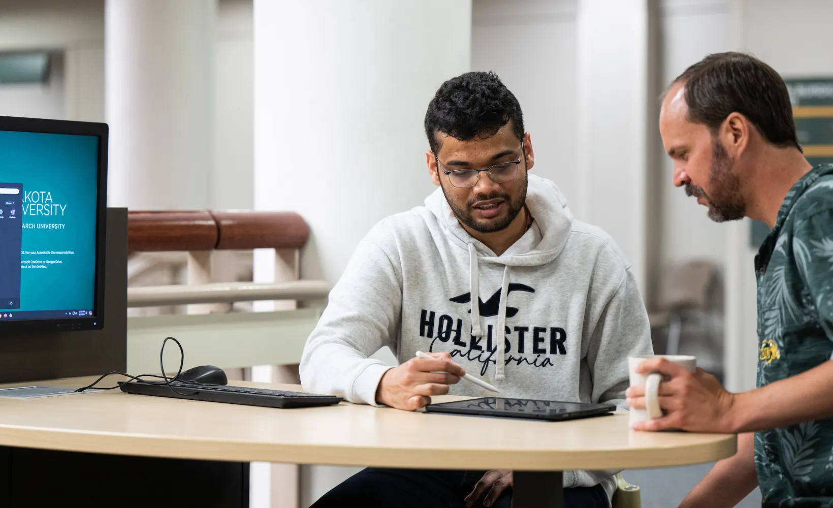 student working with a professor reviewing a project on a tablet