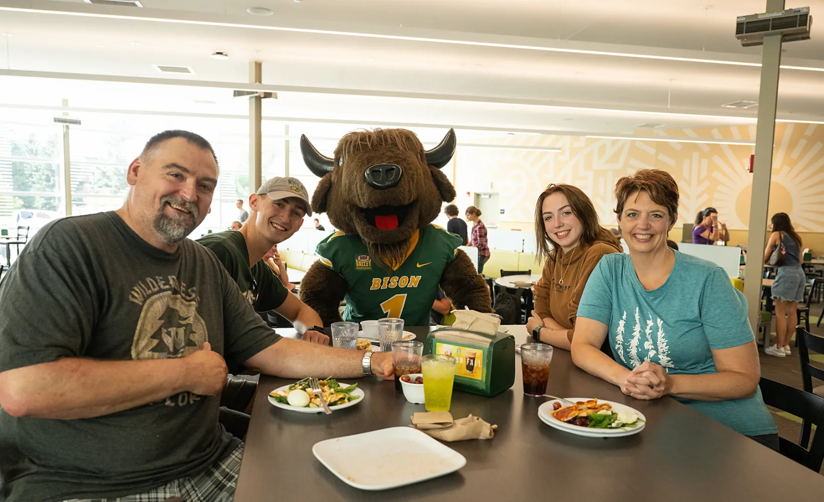 a new student with their family sitting with NDSU mascot, Thundar, at the Dining Center