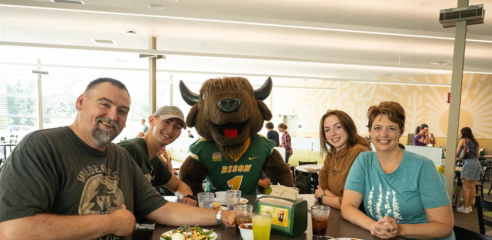 a new student with their family sitting with NDSU mascot, Thundar, at the Dining Center