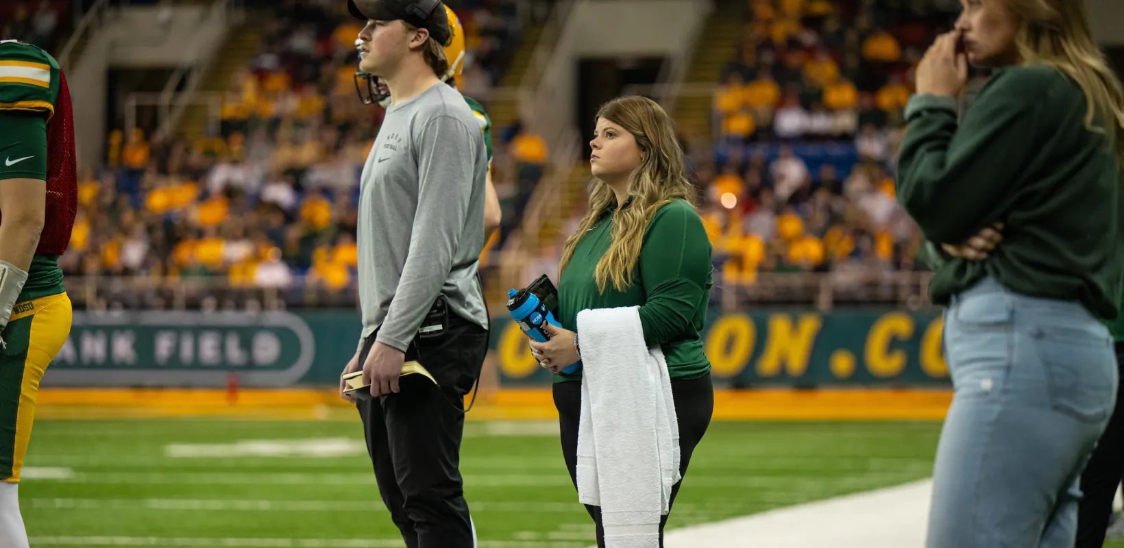 people standing on the sideline of a football game