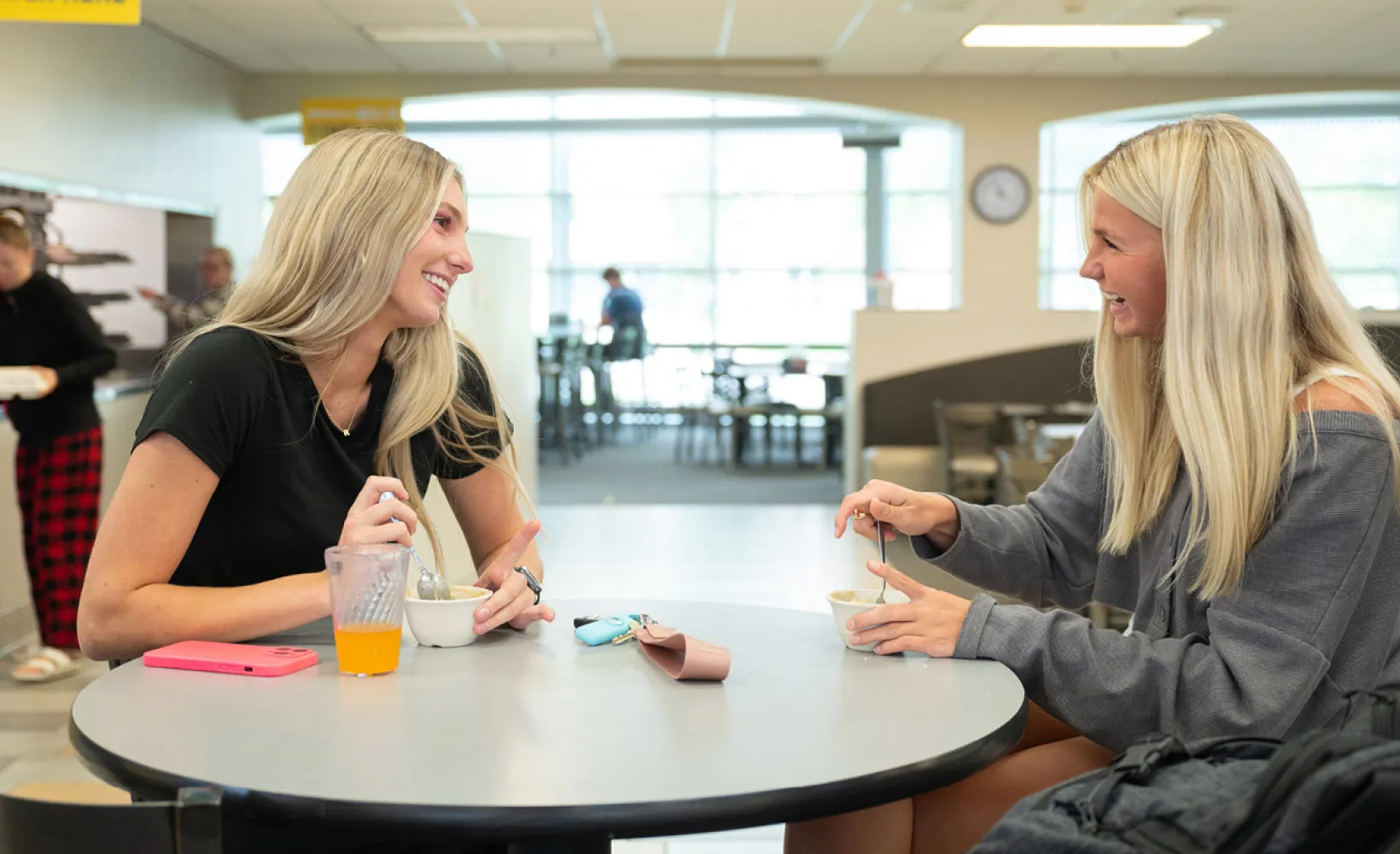 Two women sitting at a table in the Dining Center having a funny conversation