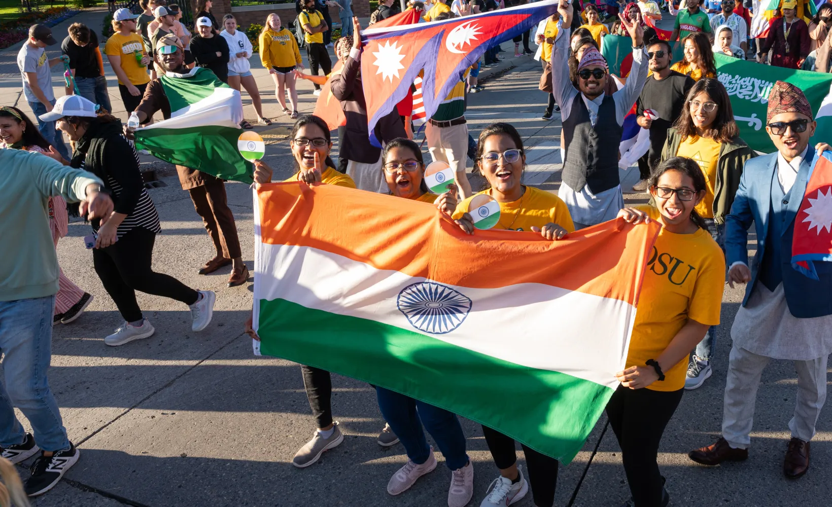 Students in a parade holding various country flags