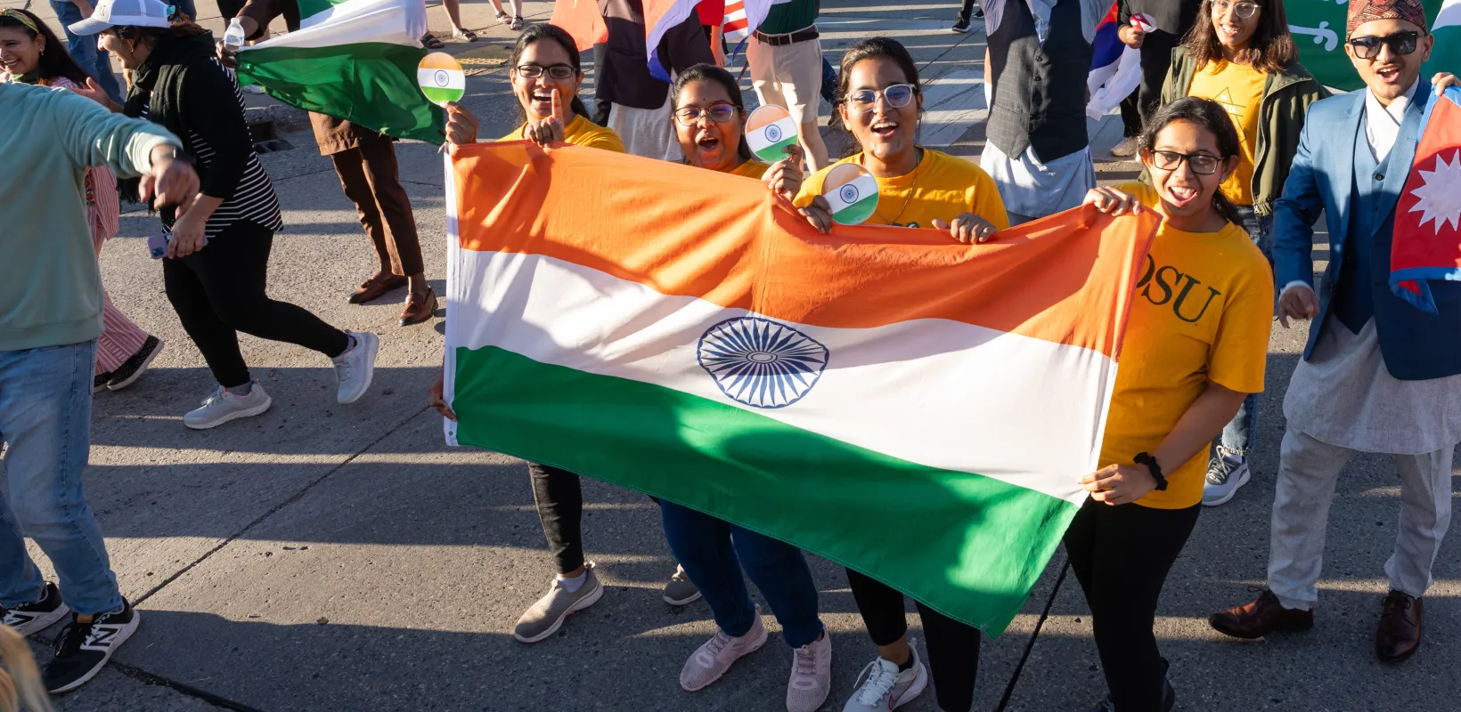 Students in a parade holding various country flags