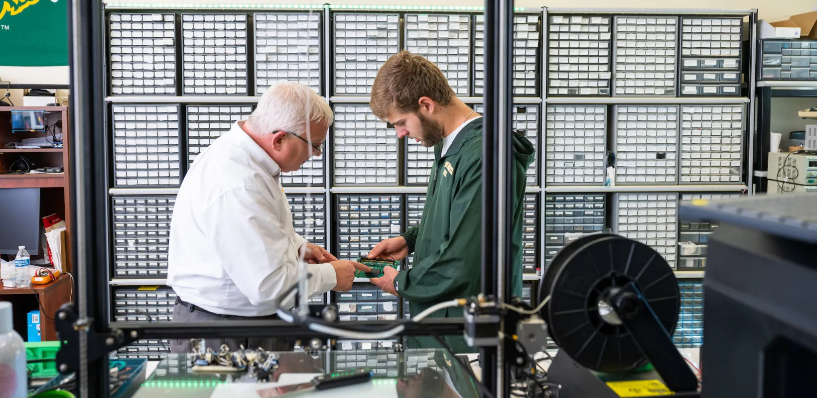 student and faculty member looking at circuit board in a lab
