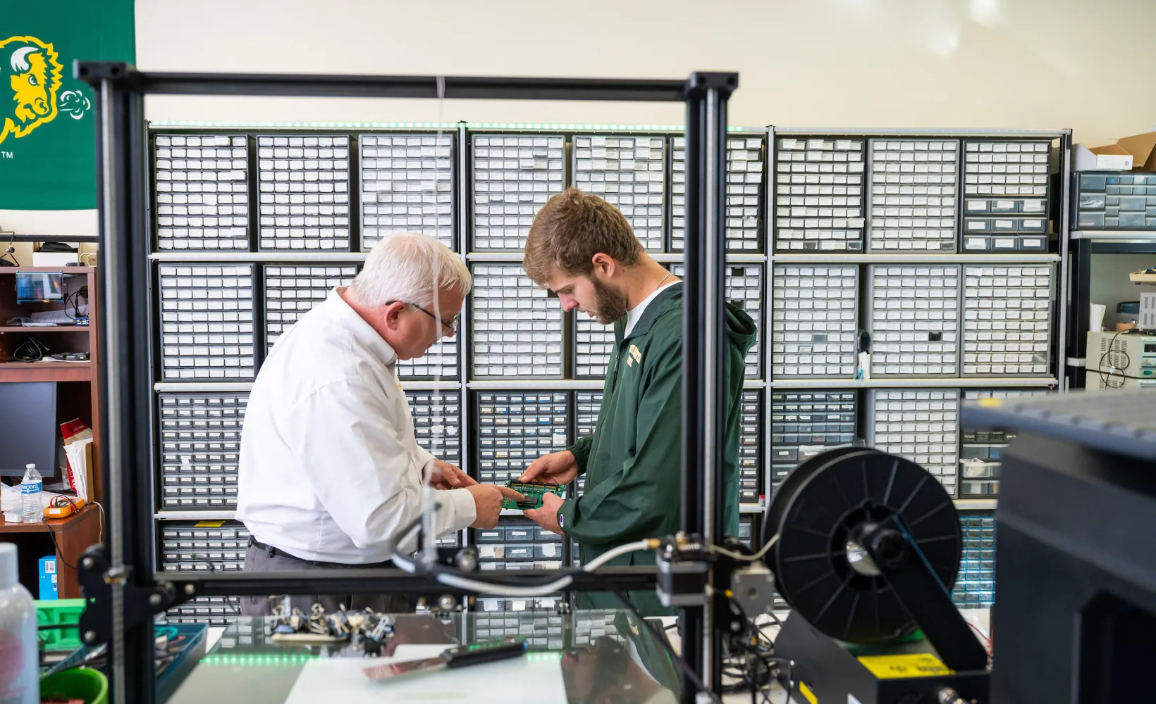 student and faculty member looking at circuit board in a lab