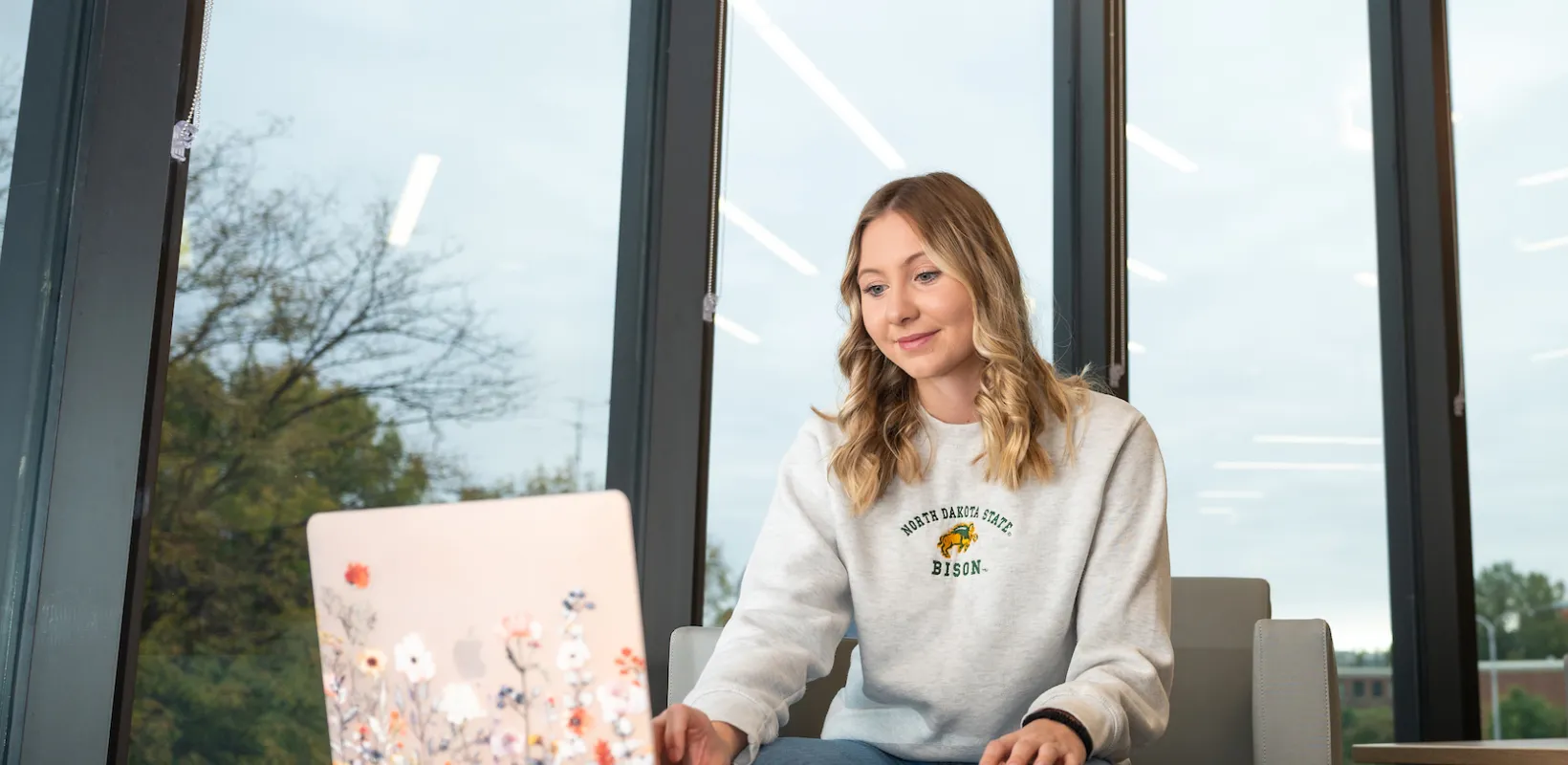 student working on a laptop with a bookbag nearby