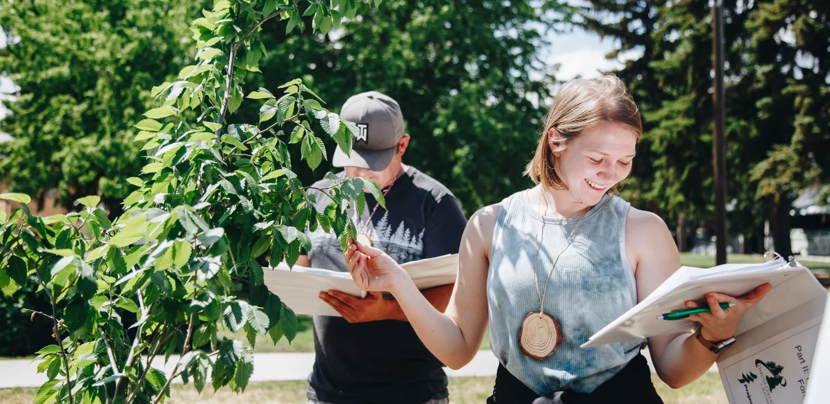 A young woman examines leaves on a tree