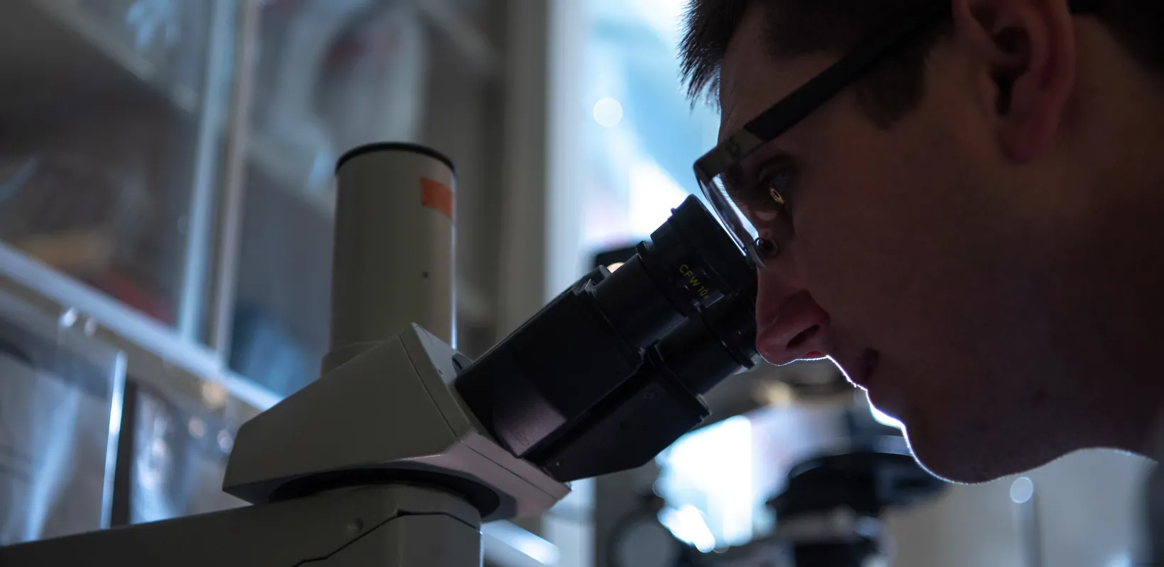 close up of student looking through microscope