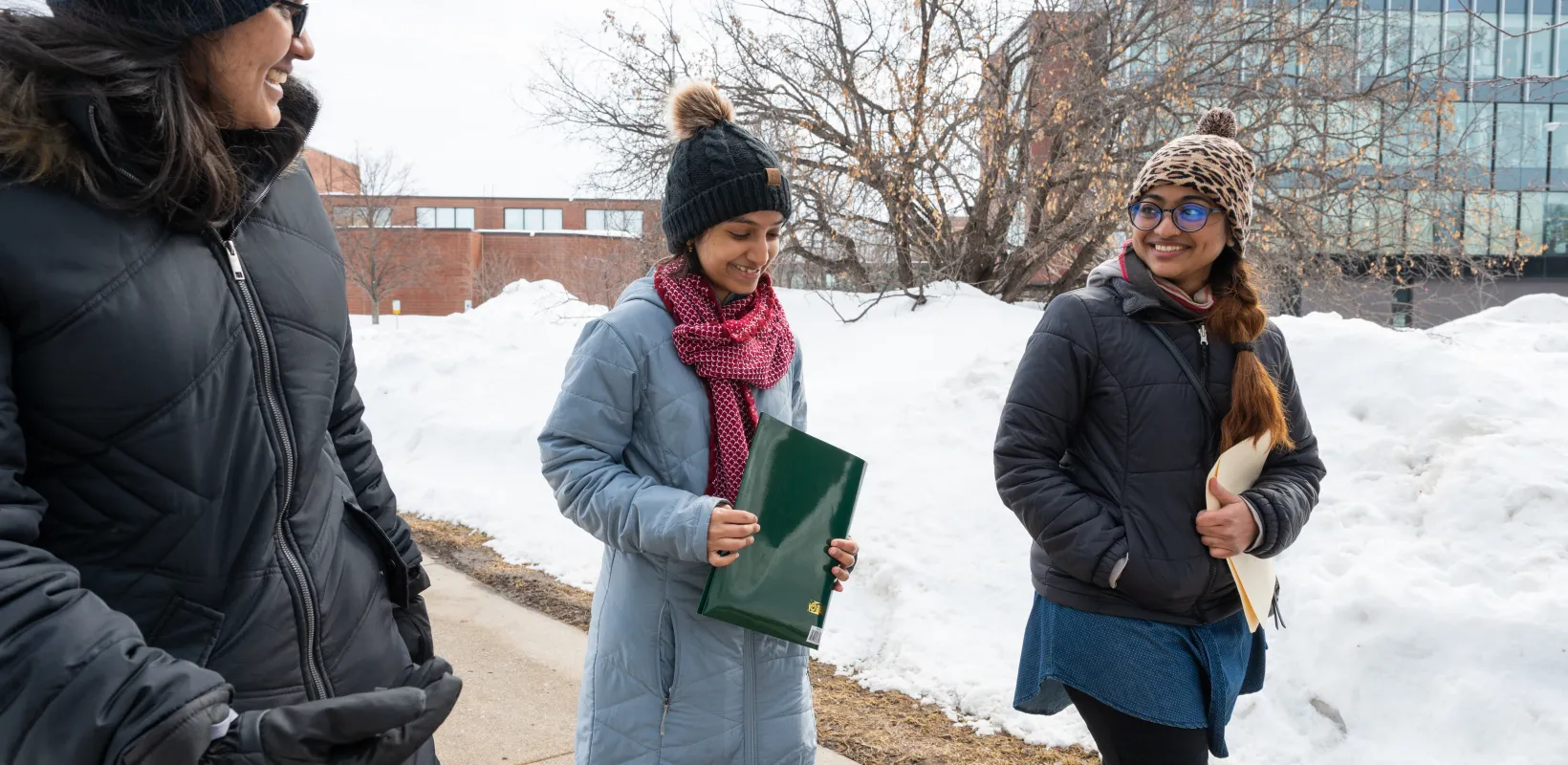 3 students walking side by side in the snow